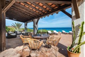 eine Terrasse mit einem Tisch, Stühlen und Meerblick in der Unterkunft Senrramada in Playa Migjorn