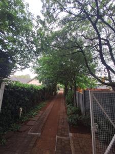 a brick road with trees and a fence at Die Eend in Centurion