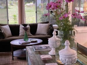een woonkamer met een bank en een tafel met bloemen bij The Vigneron's Cottage at Dragonfly Estate Vineyard - Stanthorpe in Severnlea