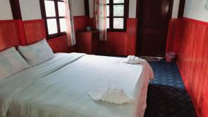 a bedroom with a white bed with red walls and windows at Rainbow guest House in Ban Pho Touane