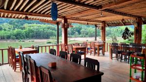 a restaurant with wooden tables and chairs on a deck at Rainbow guest House in Ban Pho Touane
