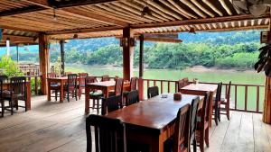 a restaurant with tables and chairs and a view of a river at Rainbow guest House in Ban Pho Touane