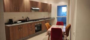 a kitchen with wooden cabinets and a table with red chairs at APPARTEMENT haut standing in Ben Slimane