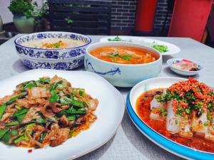 a table with plates of food and bowls of soup at Wenjun Courtyard Hotel ---5 mins walk from Tonghuimen metro station, near Tianfu square, close by culture park and Sichuan opera house, English speaking service, local tours in Chengdu