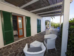 a patio with green doors and white chairs and tables at Hotel Aurora in Chiessi