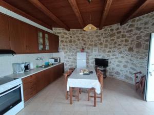 uma cozinha com uma mesa e uma parede de pedra em Rokka Pyrgos Amazing View - Maistros em Falelianá