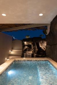 a swimming pool in a house with a rock wall at Aegean Diamonds Luxury Suites in Monolithos