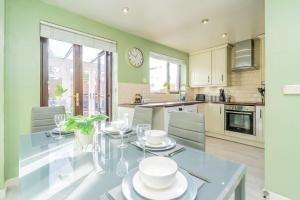 a kitchen with a glass table with plates on it at Central MK Comfy FAMILY CONTRACTOR 3B house Free Parking managed by Chique Properties Ltd in Shenley Lodge