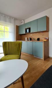 uma cozinha com uma cadeira verde e uma mesa em Apartamenty Dębowa 3 em Polanica-Zdrój