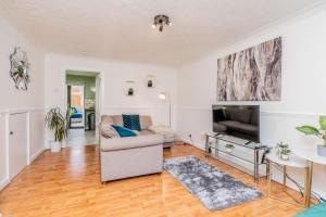 a living room with a couch and a tv at Central MK Comfy FAMILY CONTRACTOR 3B house Free Parking managed by Chique Properties Ltd in Shenley Lodge
