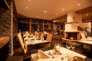 un restaurant avec des tables, des chaises et une cheminée dans l'établissement Quellenhof UNIQUE, à Loèche-les-Bains