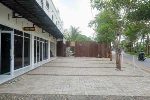 un trottoir devant un bâtiment avec un arbre dans l'établissement RedDoorz near Terminal Bus Purwokerto, à Banyumas