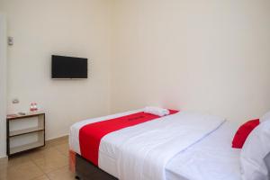- une chambre avec un lit et une télévision murale dans l'établissement RedDoorz near Terminal Bus Purwokerto, à Banyumas