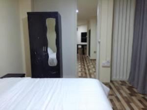 a bedroom with a white bed and a black cabinet at Aizawl Guest House, Aizwal in Āīzawl