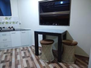 a kitchen with a table with two stools and a microwave at Aizawl Guest House, Aizwal in Āīzawl