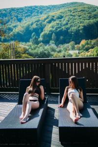 dwie kobiety w strojach kąpielowych siedzące na ławkach na pokładzie w obiekcie BRB Park Hotel w mieście Vizhenka