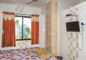 um quarto com uma cama e uma televisão de ecrã plano em Raj Lodging Satara em Satara