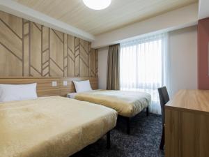 a hotel room with two beds and a window at Kyoto Plaza Hotel Kintetsu Jujo in Kyoto