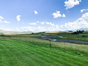 a grassy field with a river in the middle at Penwarn Farm Lodge in Drakensberg Garden