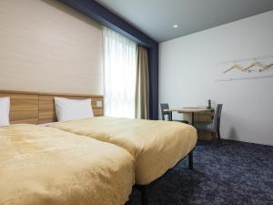 a hotel room with a large bed and a desk at Kyoto Plaza Hotel Kintetsu Jujo in Kyoto