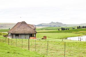 an old house in a field next to a fence at Penwarn Farm Lodge in Drakensberg Garden