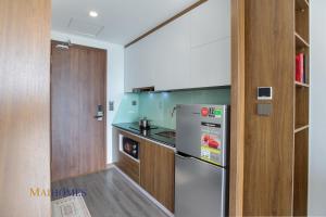 a kitchen with a stainless steel refrigerator and wooden cabinets at Maihomes Hotel Vĩnh Yên Vĩnh Phúc in Yen