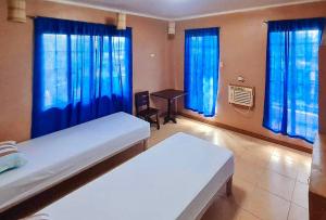a room with two beds and blue curtains at RedDoorz @ D'Little Egg Hostel Pangasinan in Urdaneta