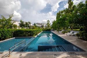 a large swimming pool with chairs and trees at Townhouse in the Wonderland in Bang Tao Beach