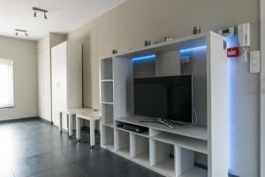 een woonkamer met een tv en witte planken bij Vakantiewoningen De Jud in Maasmechelen