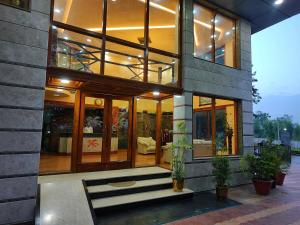Hotel Presidency Kempegowda International Airport Bangalore في دافانهالي: منزل أمامه نوافذ زجاجية ونباتات