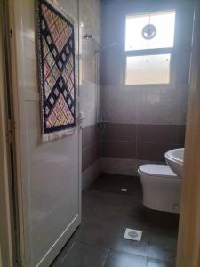 a bathroom with a toilet and a window at Villa Ria RAK in Ras al Khaimah