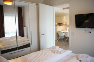 a bedroom with a bed and a tv and a mirror at Ostsee - Appartement Nr 171 "Dünengras" im Strand Resort in Heiligenhafen