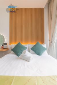 uma cama branca com duas almofadas verdes em The Shore Kota Kinabalu By Perfect Host Borneo em Kota Kinabalu