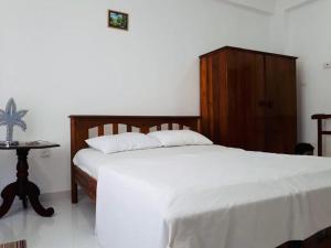 a bedroom with a white bed and a wooden cabinet at Rideway wellawatte in Colombo