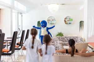 un grupo de niños viendo un personaje en una sala de estar en Hotel Las Vegas, en Bibione