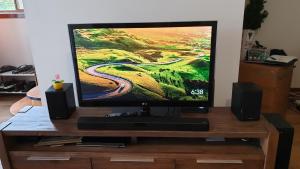 a flat screen tv on a wooden stand with speakers at Clayton Living Town House at Monash Doorstep in Clayton North