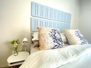 a bedroom with a white bed with a blue headboard at Stay on Main in Paarl