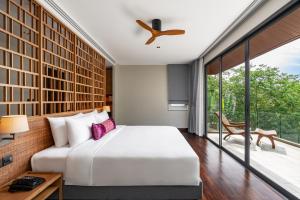 um quarto com uma cama branca e uma varanda em Noku Phuket em Chalong