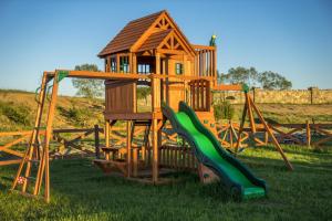 a wooden playground with a house and a slide at Hotel Kiston in Sulęczyno