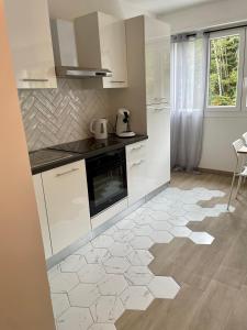 羅亞的住宿－F2 Au cœur des volcans d’Auvergne，厨房配有白色橱柜和瓷砖地板。