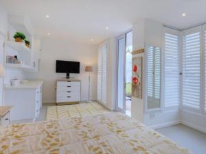 a white bedroom with a bed and a television at Beautiful Gate in George