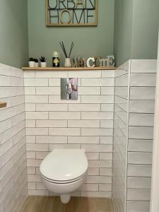 uma casa de banho com um WC com paredes em azulejos brancos em F2 Au cœur des volcans d’Auvergne em Royat