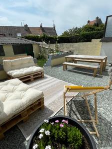 un patio con 2 divani, una panca e fiori di Maison 2 chambres Cavaignac a Calais