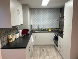 a kitchen with white cabinets and black counter tops at Modern big 2 bedroom in Northolt with terrace parking in Northolt
