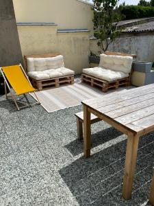 un patio con tavolo e sedie in legno e panca di Maison 2 chambres Cavaignac a Calais