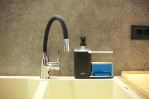 a bathroom sink with a soap dispenser next to a faucet at Modern and Luxury apartment in Athens