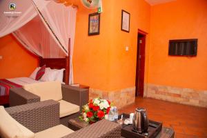a hotel room with a bed and a living room with orange walls at Kabalega Resort - Masindi in Masindi
