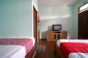 a room with two beds and a tv on a wooden cabinet at OYO 93248 Villa Syariah Astuti Lestari in Bandung