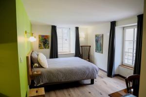 ein Schlafzimmer mit einem Bett und zwei Fenstern in der Unterkunft Les 7 Frères in Monestier-de-Clermont
