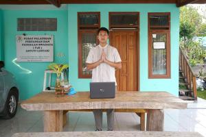 a man standing in front of a table with a laptop at OYO 93248 Villa Syariah Astuti Lestari in Bandung